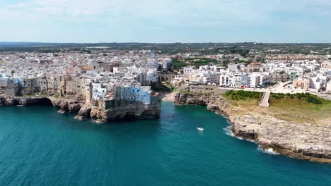 Amplia-Rotación-Aérea-De-La-Playa-De-Lama-Monachile-Rodeada-Por-La-Ciudad-Junto-Al-Acantilado-De-Polignano-A-Mare,-Italia