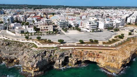 Flug-über-Die-Felsige-Küste-Apuliens-Mit-Der-Stadt-Polignano-A-Mare-Im-Hintergrund,-Italien