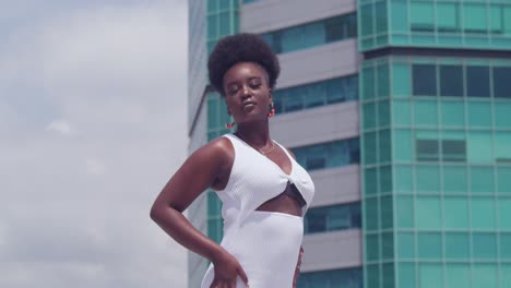 In-a-white-dress,-a-young-black-girl-stands-on-a-rooftop,-admiring-the-city