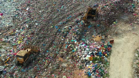 Aerial-birds-eye-view,-drone-flyover-a-sprawling-landfill-with-vast,-unsorted-waste-piles,-showcasing-environmental-sustainability-concerns-and-the-consequences-of-global-warming-and-climate-change