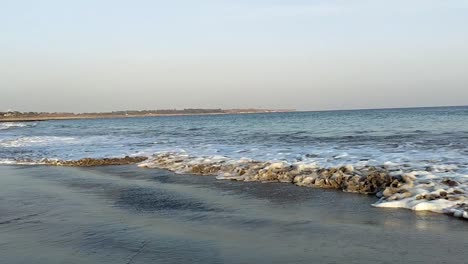 Schöner-Strand-Mit-Wellen-Aus-Blauem,-Ruhigem-Wasser,-Die-Sich-Nähern-Und-Wieder-Zurückziehen,-Mit-Klarem-Himmel-Im-Hintergrund,-Full-HD