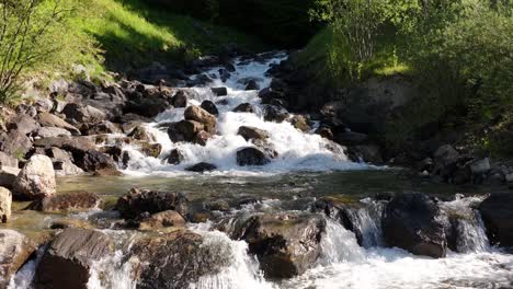 Rushing-stream-with-clear-water-flowing-over-rocks-surrounded-by-greenery-in-Weesen,-Switzerland---slow-motion