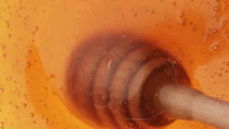 Close-up-shot-of-wooden-spoon-stirring-and-mixing-liquid-honey