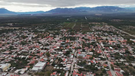 Aerial-drone-shot-of-cafayate-town-of-salta-in-Argentina-with-Andean-Cordillera-Mountain-Range-and-vineyard-farms-in-background