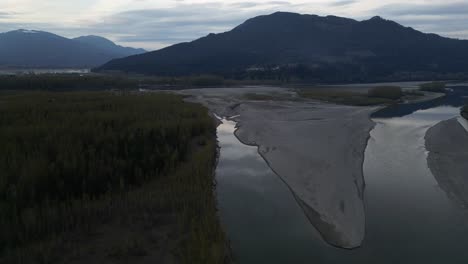 River,-Shore-with-Trees-and-Mountains-at-Sunset