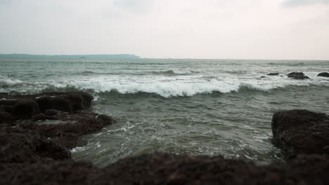 Waves-crashing-on-rocky-shore-under-cloudy-sky-during-daytime