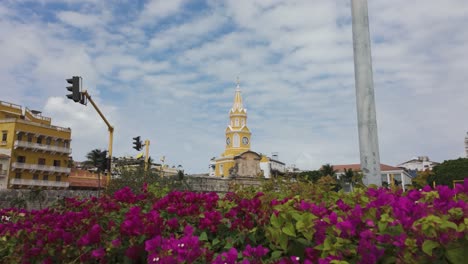 Icónico-Monumento-Torre-Del-Reloj-En-Cartagena-Con-Flores-Vibrantes-Y-Cielo-Despejado,-Colombia