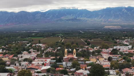 Drohnenaufnahme-Der-Stadt-Cafayate-In-Argentinien-Mit-Der-Andenkordillere-Im-Hintergrund