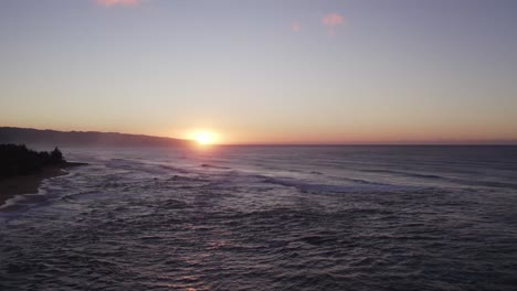 Ein-Atemberaubender-Sonnenuntergang-über-Der-Nordküste-Von-Oahu,-Bei-Dem-Die-Goldene-Sonne-Hinter-Dem-Horizont-Verschwindet-Und-Einen-Warmen-Glanz-über-Die-Ruhigen-Wellen-Des-Pazifischen-Ozeans-Wirft