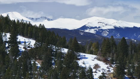 Mount-Evans-Blue-Sky-aerial-drone-parallax-North-Turkey-Creek-Marshdale-Evergreen-Colorado-USA-winter-spring-fresh-snow-melting-blue-sky-morning-sunny-cloudy-Rocky-Mountains-to-right-motion