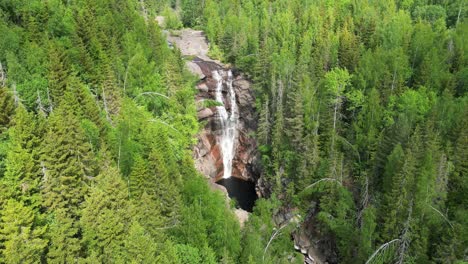 Drone-footage-captures-the-Solbergfossen-waterfall-surrounded-by-dense-green-forest-in-Norway