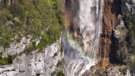 Seerenbachfälle-Mit-Einem-Leuchtenden-Regenbogen,-Die-In-üppiger-Umgebung-Eine-Steile-Klippe-Hinabstürzen,-Schweiz