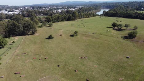 Vista-Aérea-De-Un-Parque-De-Entrenamiento-De-Caballos-Cerca-De-Un-Río-Con-Casas-Residenciales-Al-Otro-Lado-Del-Río.