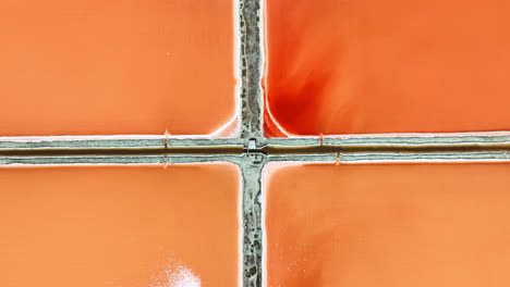 Birds-eye-drone-shot-above-red-Salt-production-pools,-sunny-day-in-Albania