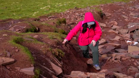 Exhausted-woman-climbing-a-mountain-through-a-muddy-and-rocky-terrain