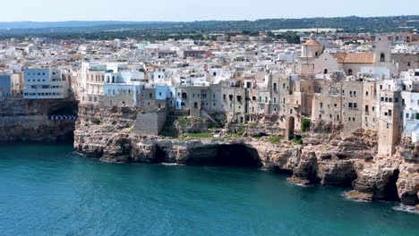 Vista-Aérea-Giratoria-De-Polignano-A-Mare-Ciudad-Al-Borde-De-Un-Acantilado-Escarpado-En-Puglia,-Italia