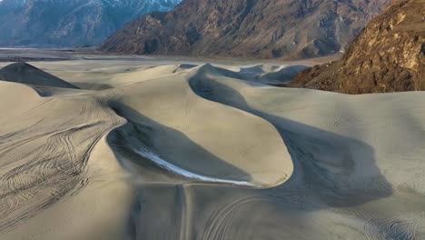 Dunas-De-Arena-En-El-Frío-Desierto-De-Sarfaranga-Con-Huellas-De-Neumáticos,-Valle-De-Skardu---Paso-Elevado-Aéreo