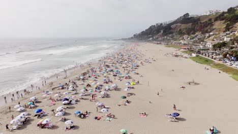 Vuelo-Aéreo-Sobre-La-Playa-Maitencillo-Con-Bañistas-Y-Coloridas-Sombrillas