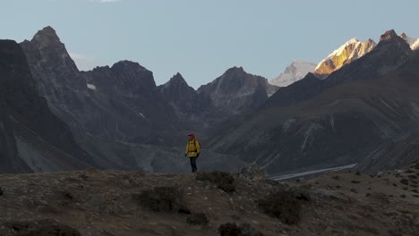 Un-Dron-Captura-A-Un-Excursionista-En-El-Campamento-Base-Del-Everest,-Nepal,-Disfrutando-De-Las-Majestuosas-Vistas-De-Las-Montañas-Durante-La-Hora-Dorada-Del-Atardecer.