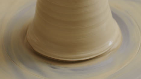 Close-up-shot-of-removing-a-clay-finished-vase-from-the-potters-wheel,-using-a-special-technique-with-a-small-string,-not-damaging-the-vase-in-the-process