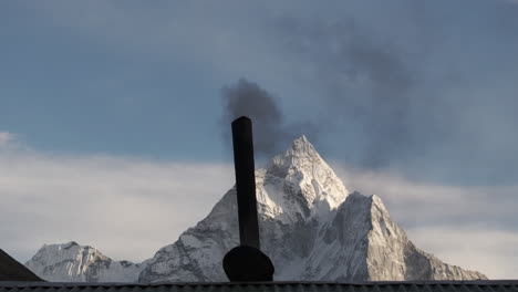 Un-Dron-Captura-El-Humo-De-Una-Chimenea-En-El-Campamento-Base-Del-Everest,-Nepal,-Destacando-La-Contaminación-Ambiental-Y-El-Cambio-Climático-Con-Ama-Dablam-De-Fondo,-Una-Casa-De-Té-Local-En-El-Paso-De-Thukla