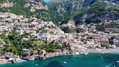 Vista-Cercana-De-Las-Coloridas-Casas-Costeras-De-Positano,-Rodeadas-De-Exuberante-Vegetación,-Aguas-Turquesas-Y-Barcos,-Costa-De-Amalfi,-Italia,-Europa