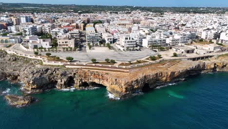 Vista-De-Arriba-Hacia-Abajo-De-Un-Acantilado-Escarpado-Frente-Al-Mar,-Olas,-Agua-Turquesa,-En-Polignano-A-Mare,-Italia