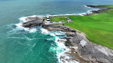 Irlands-Epische-Orte-Wellen,-Die-An-Einem-Windigen-Sommertag-Auf-Die-Felsen-Unterhalb-Des-Hook-Head-Leuchtturms-An-Der-Küste-Von-Wexford-Krachen