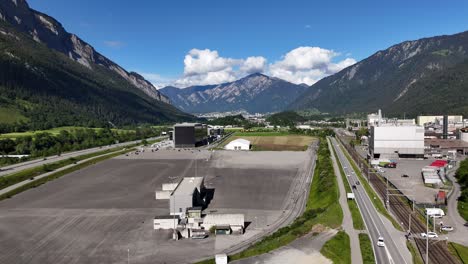 Zona-Industrial-Y-Carretera-Con-Montañas-Al-Fondo-En-Domat-Ems,-Suiza.