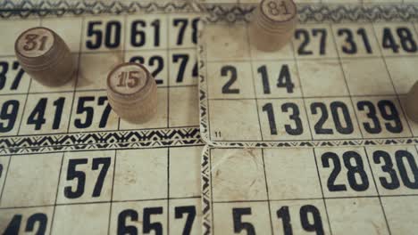 Macro-video-of-a-Bingo-board,-studio-lights,-120-fps,-slow-motion,-wooden-chip-digits,-Raw-footage,-lottery-desk-game,-card-numbers,-crane-push-in-rotating-movement-from-above