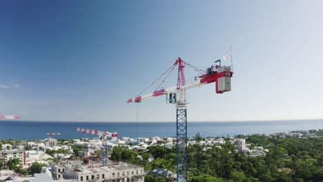 Drone-shot-of-long-cranes-present-for-construction-site-on-Reunion-Island,-France-during-sunny-day