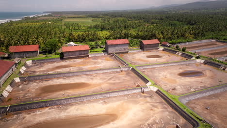 Abandoned-shrimp-farm-in-Bali-countryside-on-coastline-with-empty-ponds,-aerial