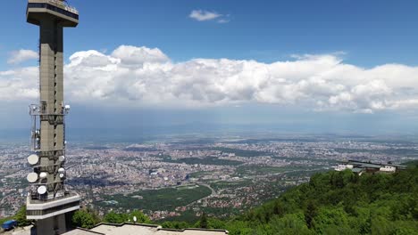 Toma-Aérea-De-Establecimiento-De-Sofía,-Bulgaria,-Junto-A-Una-Torre-De-Televisión,-En-Lo-Alto-De-Una-Montaña-En-La-Montaña-Vitosha,-En-Un-Día-Soleado-Con-Nubes-Blancas-Y-Esponjosas.