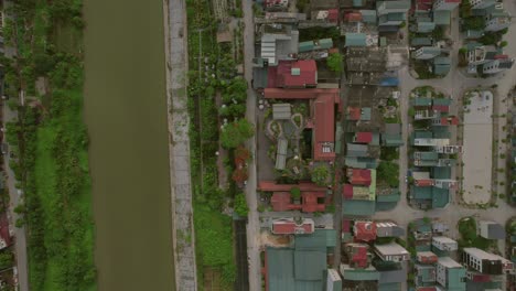 Top-down-aerial-view-of-Hanoi's-riverside-neighborhood-with-mixed-rooftops,-Vietnam