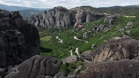 Drone-passing-over-rock-formation-revealing-Meteora-Valley-monasteries-Greece