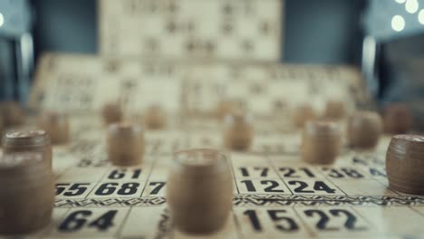 Macro-video-of-a-Bingo-board,-studio-lights,-120-fps,-slow-motion,-wooden-chip-digits,-Raw-footage,-lottery-desk-game,-card-numbers,-crane-slide-left-smooth-movement