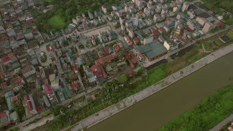 Top-down-aerial-view-of-a-residential-area-in-Hanoi,-Vietnam,-located-near-a-river-water-channel,-illustrating-the-concept-of-integrated-urban-living-and-natural-resource-management