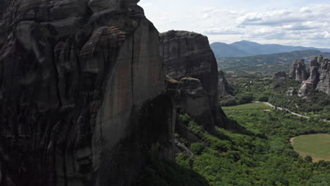 Close-up-drone-flight-near-rock-pillar-formation-revealing-Meteora-valley-Region-Greece-sunny-day