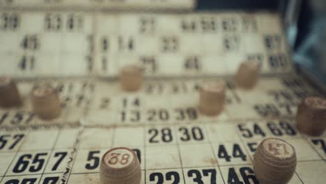 Macro-video-of-a-Bingo-board,-studio-lights,-120-fps,-slow-motion,-wooden-chip-digits,-Raw-footage,-vintage-lottery-desk-game,-card-numbers,-pull-back-shot