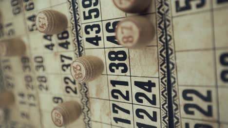 Macro-video-of-a-Bingo-board,-studio-lights,-120-fps,-slow-motion,-wooden-chip-digits,-Raw-footage,-lottery-desk-game,-card-numbers,-crane-pull-back-dreamy-rotating-movement