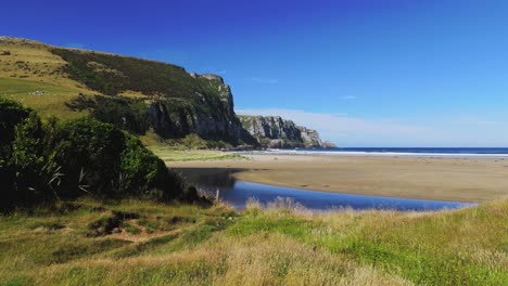 Low-angle-aerial-view-of-Purakaunui-Bay,-a-Scenic-Reserve-Catlins-Coast-in-New-Zealand-during-afternoon