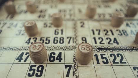 Macro-video-of-a-Bingo-board,-studio-lights,-120-fps,-slow-motion,-wooden-chip-digits,-Raw-footage,-lottery-desk-game,-card-numbers,-crane-smooth-slide-movement