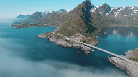 Toma-Aérea-Del-Puente-Djupfjord-En-El-Municipio-De-Moskenes,-Islas-Lofoten,-Noruega-Sobre-Un-Mar-De-Nubes