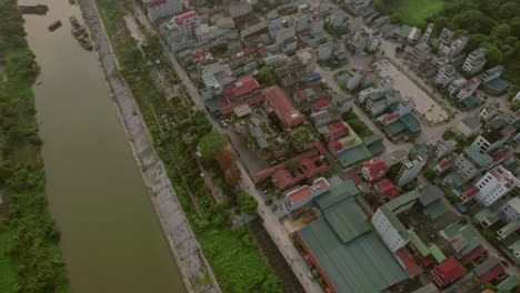 Vista-Aérea-Del-Barrio-De-Hanoi-Junto-A-Un-Río-Al-Atardecer,-Mostrando-El-Paisaje-Urbano,-Vietnam