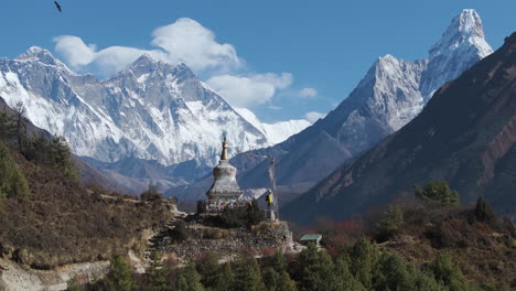 Drone-captures-a-tourist-at-a-stupa-with-stunning-views-of-Everest-and-Ama-Dablam-in-Sagarmatha-National-Park,-Nepal