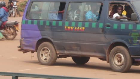 Full-Uganda-taxi-van-driving-on-dirty-street,-side-view