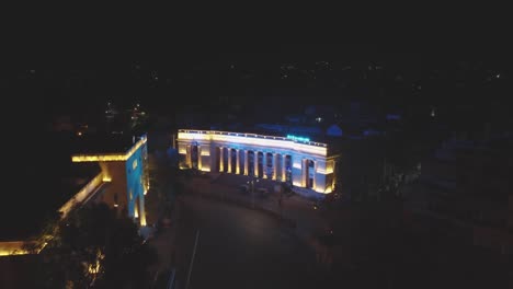 Toma-Aérea-De-Un-Edificio-De-Arquitectura-Romana-Iluminado-Durante-La-Noche-En-La-Ciudad-De-Gwalior-En-Madhya-Pradesh,-India