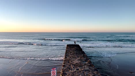 close-view-of-coach-training-surfers-at-the-tip-of-the-pier-in-Portugal