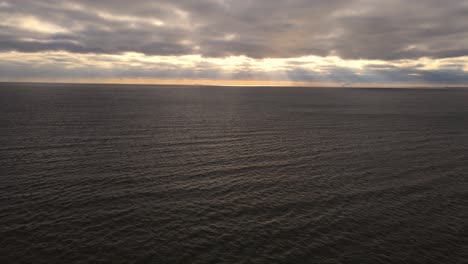 Sunset-Over-Calm-Ocean-with-Dramatic-Clouds-in-Aerial-view