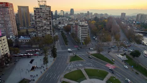 Establishing-Aerial-View-Of-Santiago-De-Chile-Plaza-Baquedano-Urban-Commercial-Area-Below-Sunset-Skyline